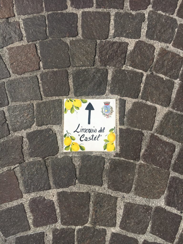 Sign on the pavement showing directions for Limonaia del Castel (Lemon museum) in Limone Sul Garda